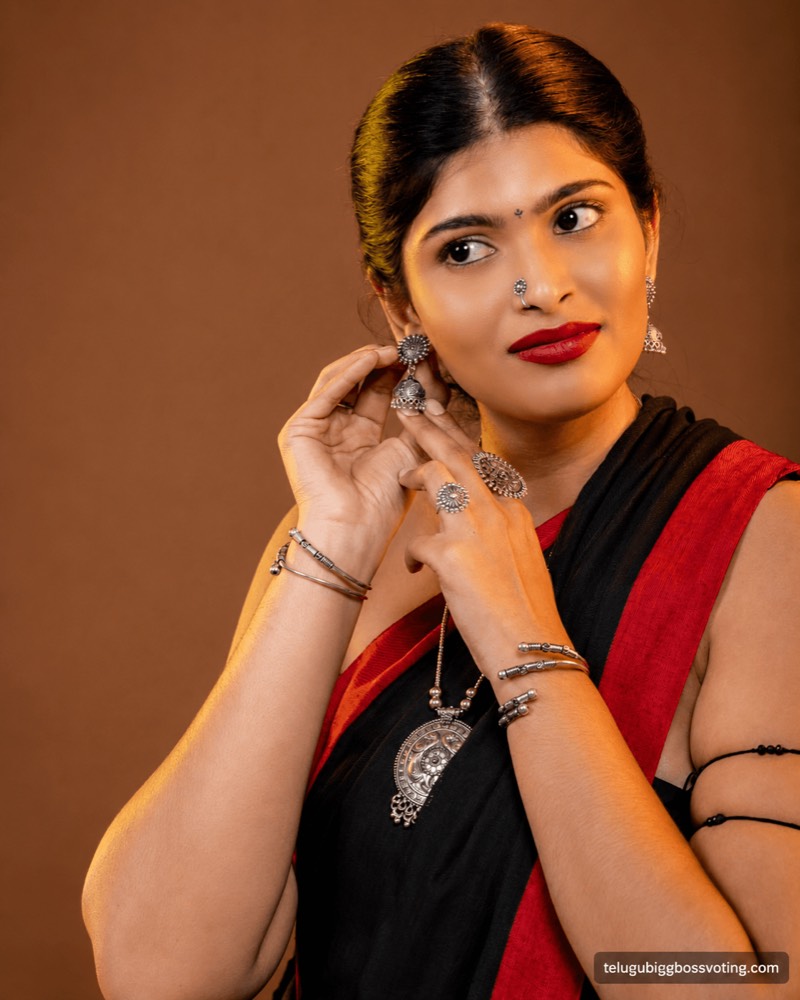 Illustrated portrait of Gayathri Vardhan in a black and red saree with oxidised silver jewellery, adjusting an earring