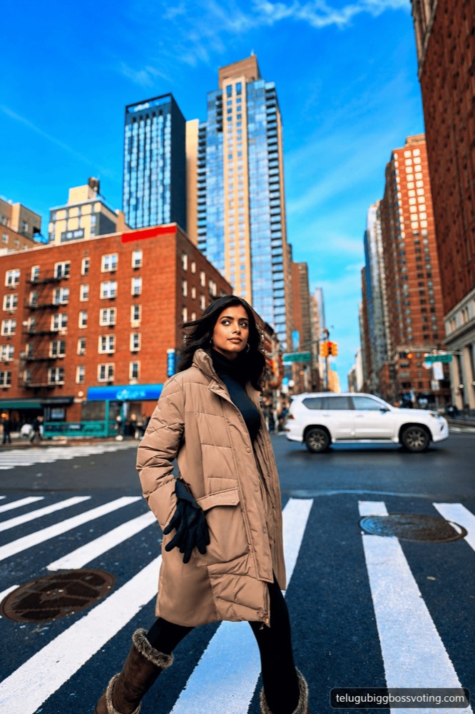 Illustrated portrait of Srishti Vyakaranam crossing a city street in a winter coat, skyscrapers behind her